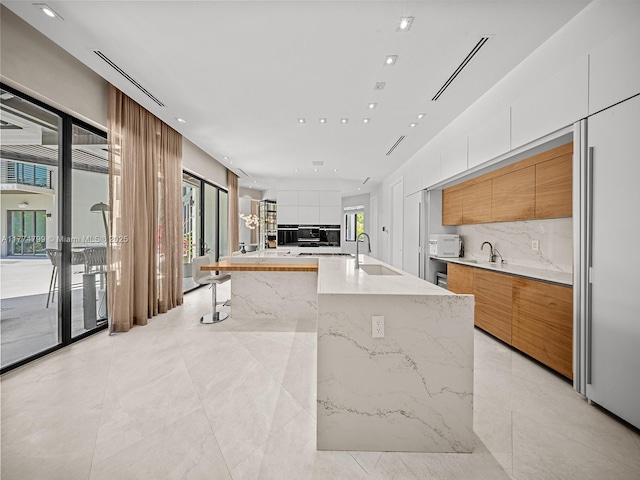 5700 SW 91st St, Pinecrest, FL 33156 - kitchen featuring modern cabinets, white microwave, decorative backsplash, a sink, and white cabinets