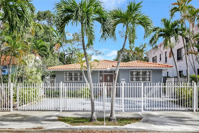 view of front of house with a fenced front yard, stucco siding, and a tiled roof