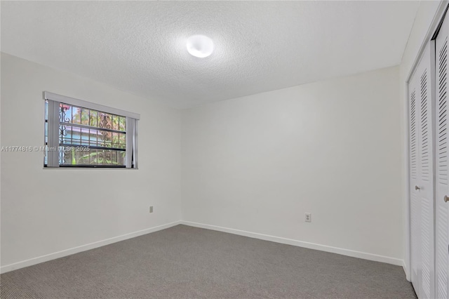unfurnished bedroom with carpet floors, a textured ceiling, a closet, and baseboards