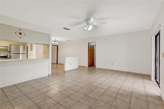 unfurnished living room with light tile patterned flooring, ceiling fan with notable chandelier, baseboards, and visible vents
