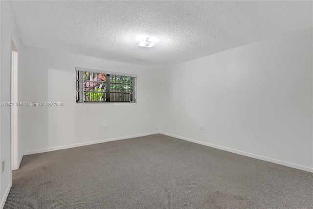 spare room with a textured ceiling, carpet flooring, and baseboards