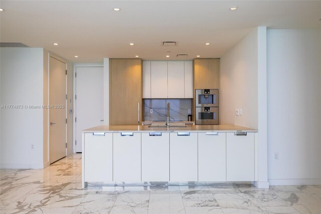 15701 Collins Ave Unit 1004, Sunny Isles Beach, FL 33160 - kitchen featuring light marble finish floors, stainless steel double oven, a sink, recessed lighting, and a peninsula
