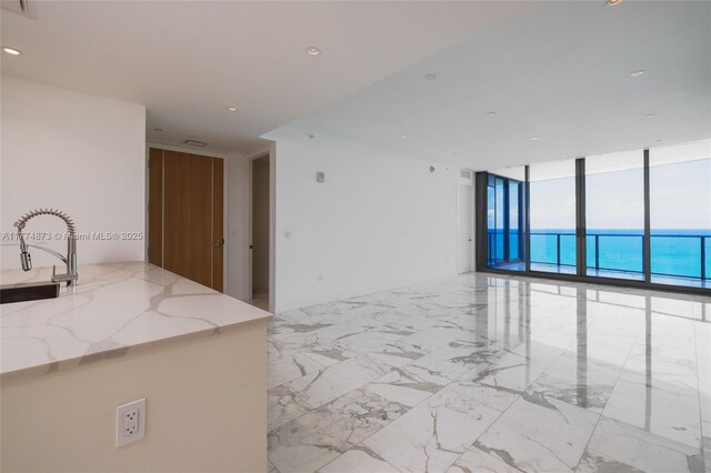 15701 Collins Ave Unit 1004, Sunny Isles Beach, FL 33160 - empty room featuring floor to ceiling windows, a sink, recessed lighting, light marble finish floors, and a water view