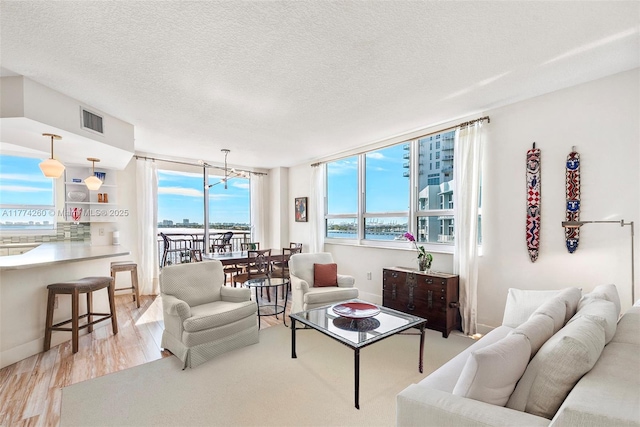 living area with plenty of natural light, a water view, visible vents, and light wood-type flooring