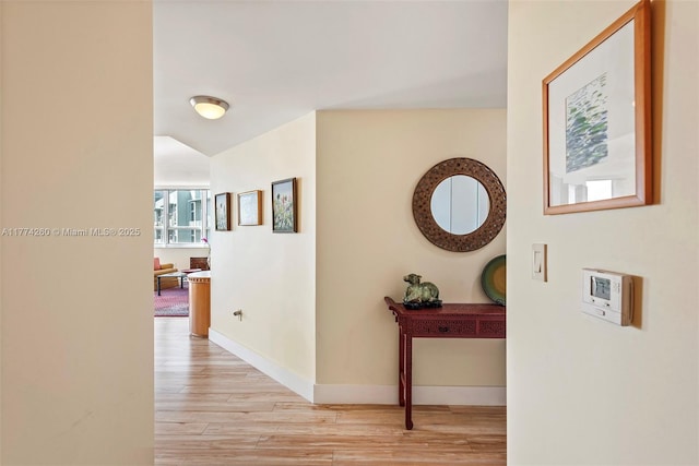 corridor with baseboards and light wood finished floors
