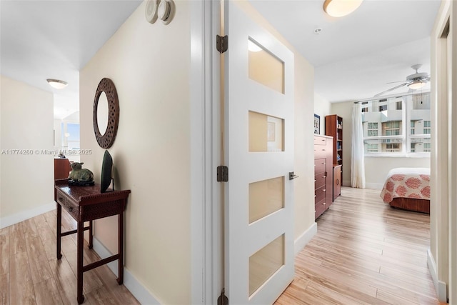 hallway featuring baseboards and light wood-style floors