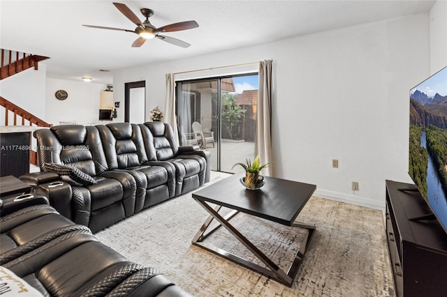 living room with wood finished floors, ceiling fan, baseboards, and stairs