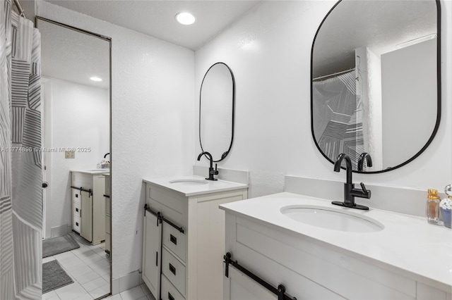 full bath with tile patterned floors, two vanities, and a sink