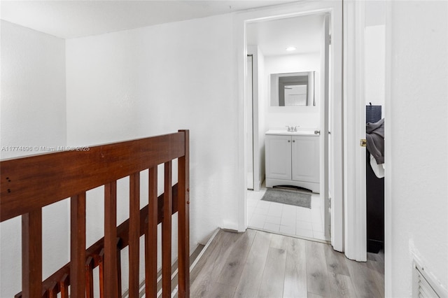hallway with a sink and light wood-style flooring