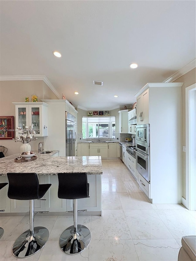 14261 SW 30th St, Miami, FL 33175 - kitchen with built in appliances, a peninsula, a kitchen breakfast bar, crown molding, and light stone countertops