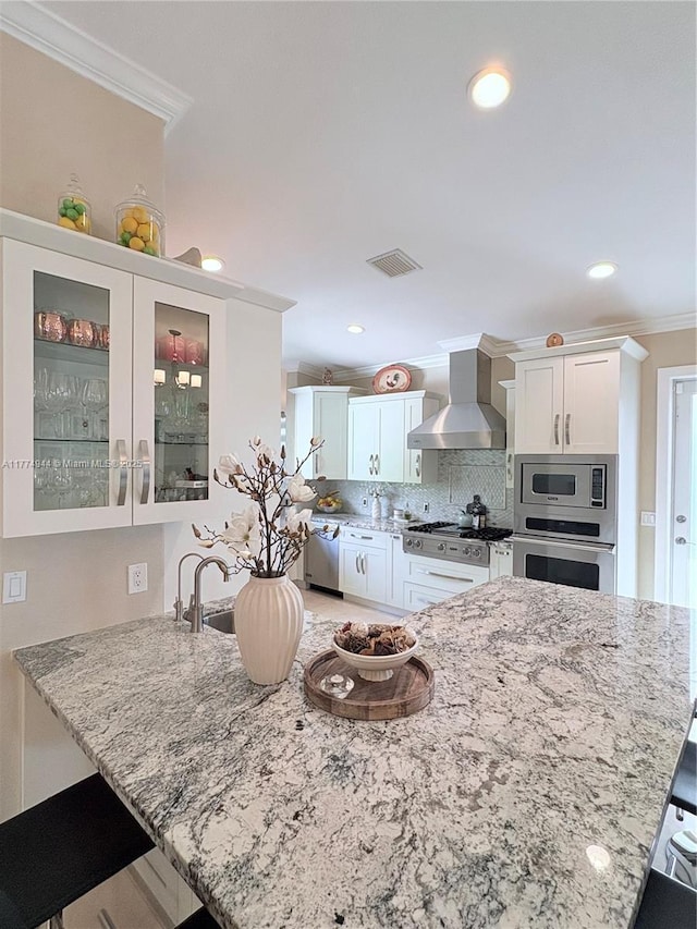 14261 SW 30th St, Miami, FL 33175 - kitchen with wall chimney range hood, appliances with stainless steel finishes, crown molding, a breakfast bar area, and light stone countertops