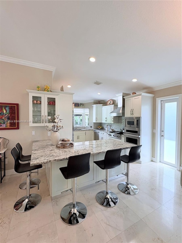 14261 SW 30th St, Miami, FL 33175 - kitchen with wall chimney exhaust hood, crown molding, stainless steel appliances, a kitchen breakfast bar, and white cabinetry
