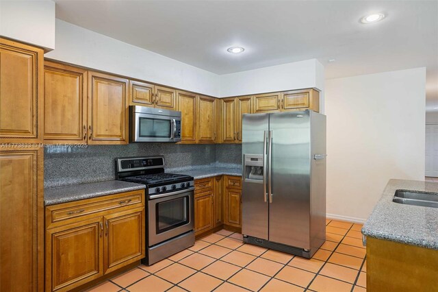 kitchen with a sink, backsplash, brown cabinets, and stainless steel appliances