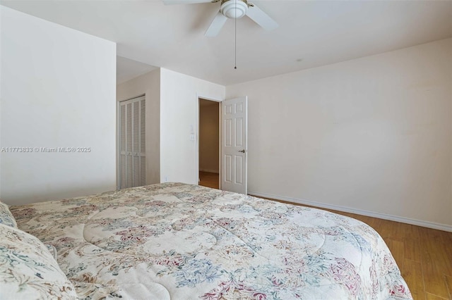 bedroom featuring a closet, a ceiling fan, baseboards, and wood finished floors