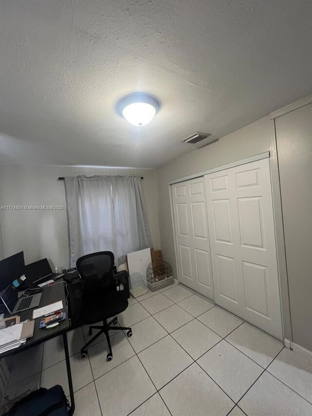 office with light tile patterned flooring, a textured ceiling, and visible vents