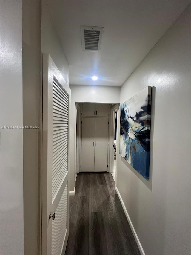 corridor with dark wood-style flooring, baseboards, and visible vents