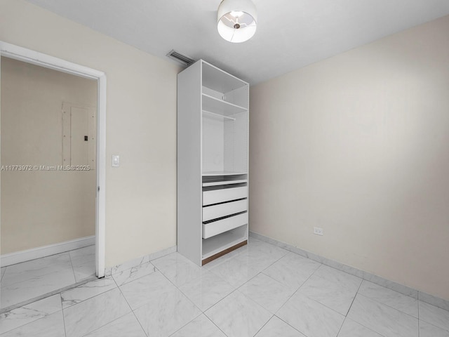 unfurnished bedroom with baseboards, marble finish floor, visible vents, and electric panel