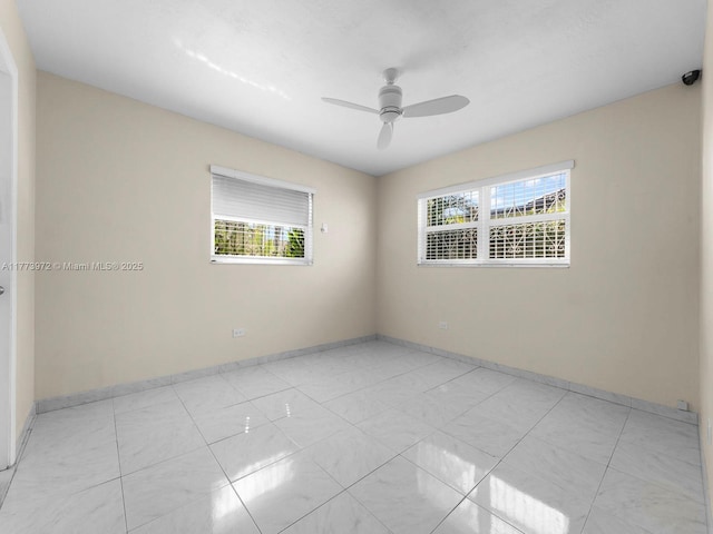spare room with a wealth of natural light, baseboards, and a ceiling fan