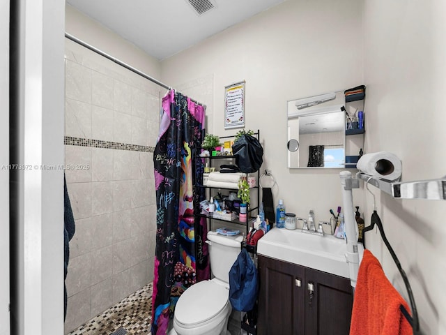 full bath with toilet, vanity, a tile shower, and visible vents