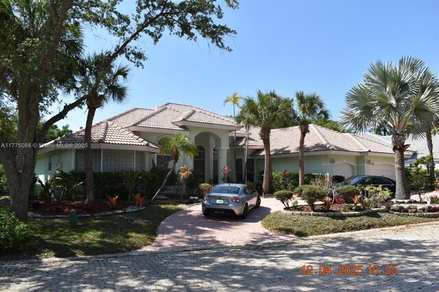 12044 NW 9th Pl, Coral Springs, FL 33071 - mediterranean / spanish house featuring a garage, stucco siding, a tile roof, and decorative driveway