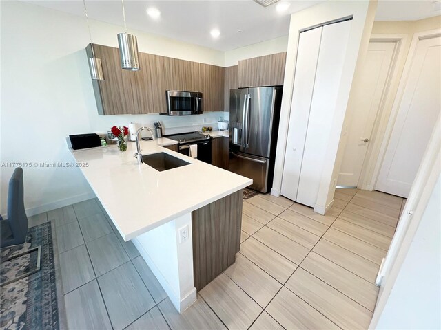 kitchen featuring light countertops, a sink, a peninsula, modern cabinets, and stainless steel appliances