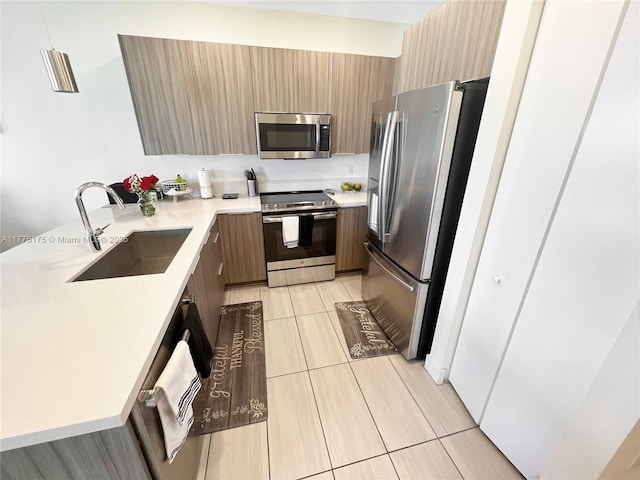 kitchen with light countertops, a peninsula, modern cabinets, appliances with stainless steel finishes, and a sink