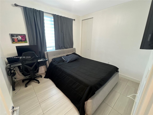 bedroom with baseboards, a closet, and light tile patterned flooring