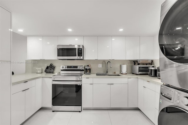 8775 Park Blvd Unit 111, Miami, FL 33172 - kitchen with a sink, stainless steel appliances, white cabinetry, modern cabinets, and stacked washer and clothes dryer