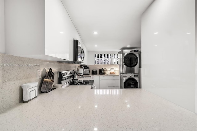 8775 Park Blvd Unit 111, Miami, FL 33172 - kitchen with backsplash, appliances with stainless steel finishes, stacked washer / drying machine, light stone counters, and white cabinetry