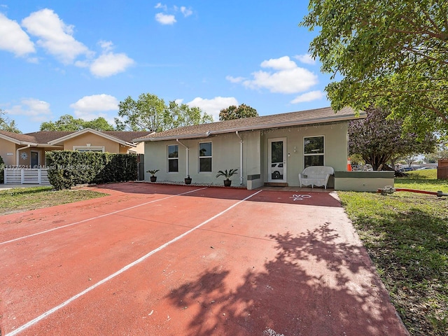 rear view of house featuring stucco siding and fence