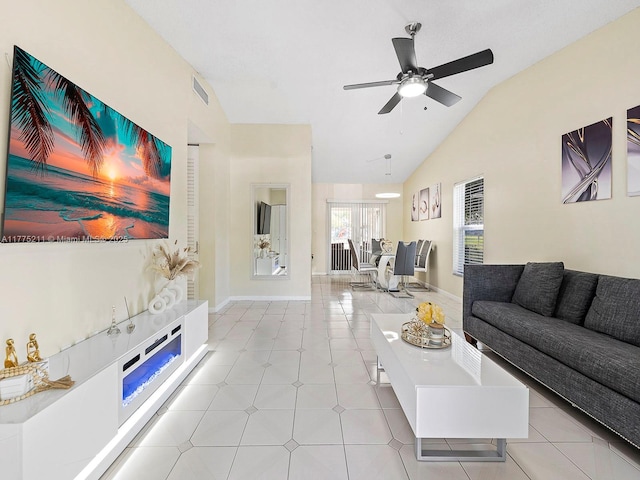 living area with light tile patterned flooring, visible vents, baseboards, a ceiling fan, and vaulted ceiling