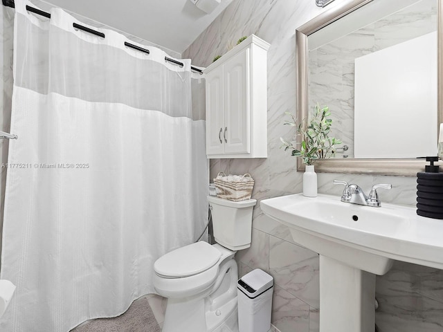 full bath with curtained shower, toilet, and tile walls