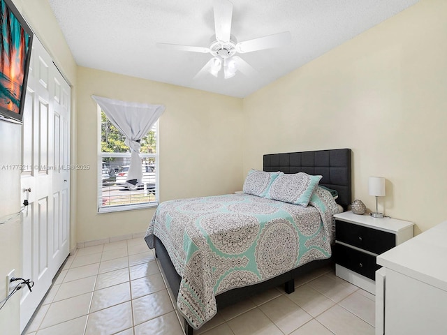bedroom with a closet, a textured ceiling, ceiling fan, and light tile patterned flooring