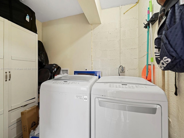 washroom with concrete block wall, washer and clothes dryer, and laundry area