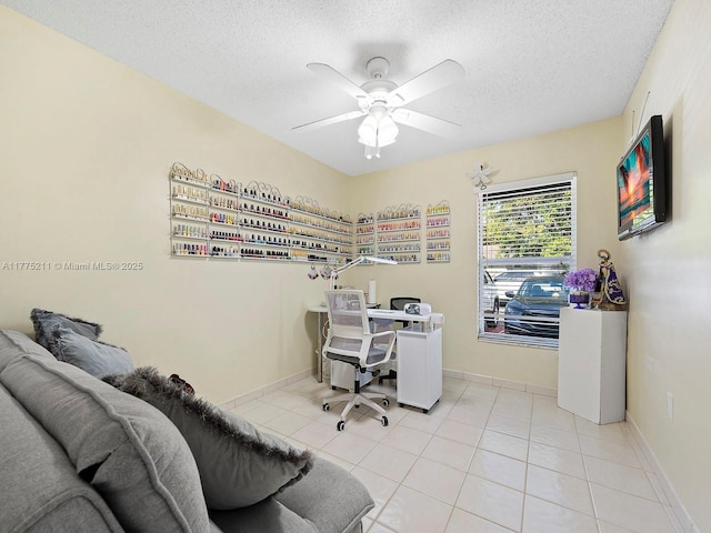home office with light tile patterned flooring, baseboards, ceiling fan, and a textured ceiling