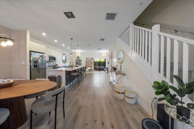 dining room with stairs, recessed lighting, baseboards, light wood finished floors, and visible vents