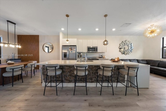 kitchen with a spacious island, white cabinetry, a kitchen breakfast bar, stainless steel appliances, and visible vents