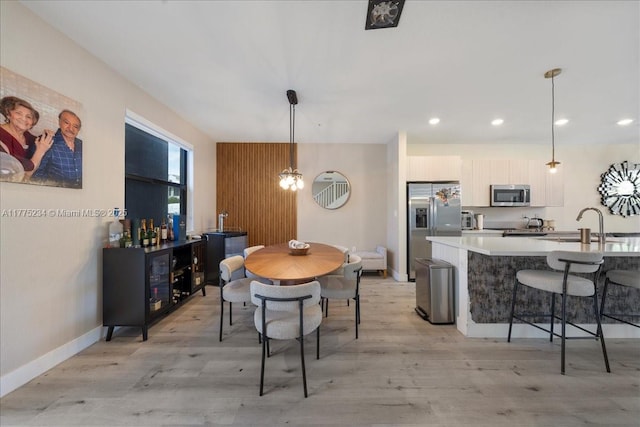 dining room featuring baseboards, light wood-type flooring, and recessed lighting