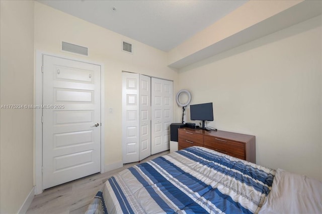 bedroom featuring baseboards, visible vents, a closet, and light wood-style floors