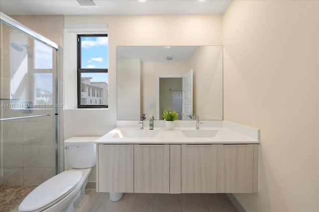 full bathroom featuring toilet, a sink, a stall shower, and double vanity
