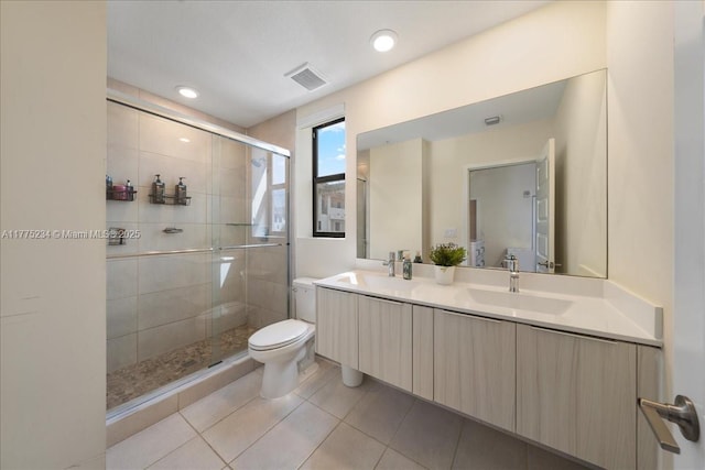 bathroom featuring toilet, a sink, a stall shower, and visible vents