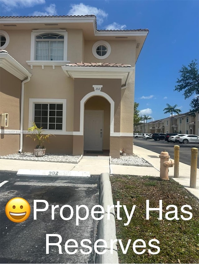 entrance to property featuring stucco siding and uncovered parking