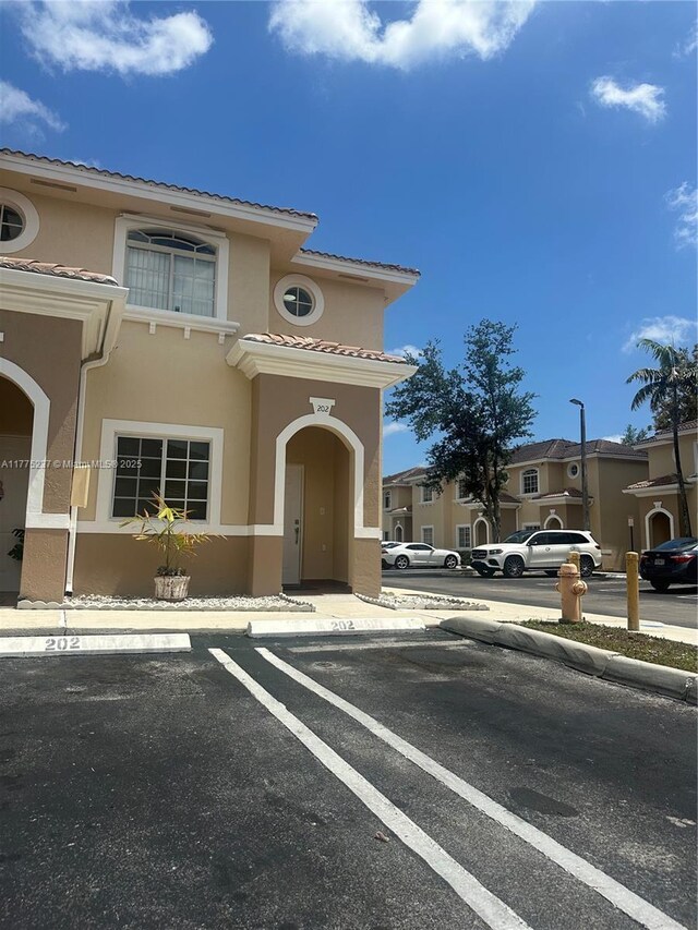 view of front of property with a tile roof, stucco siding, and uncovered parking
