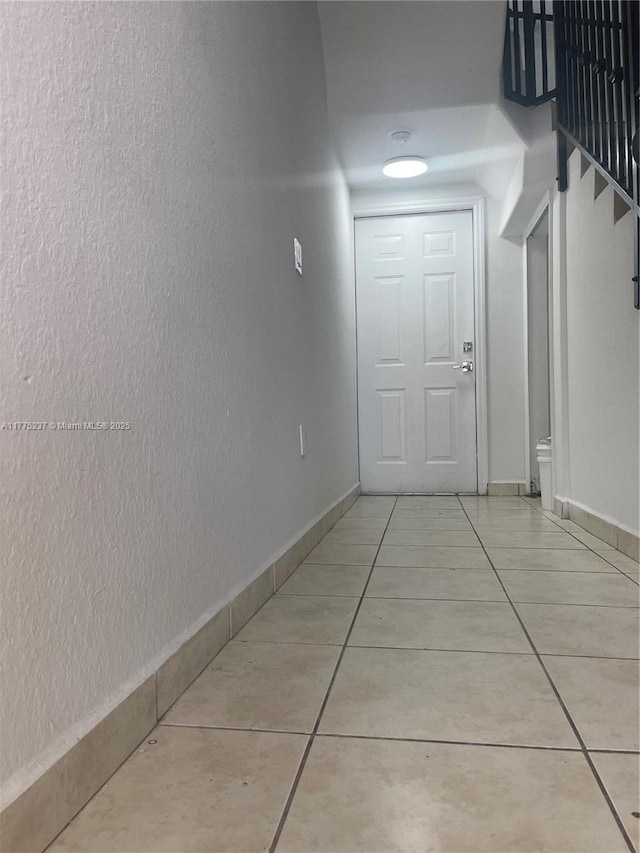 hall with stairway, tile patterned floors, and baseboards