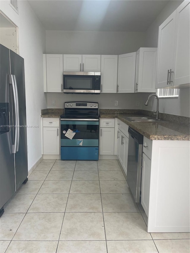 kitchen with a sink, stainless steel appliances, light tile patterned flooring, visible vents, and white cabinets