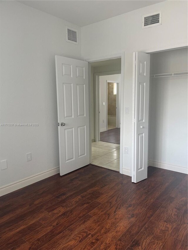 unfurnished bedroom featuring baseboards, visible vents, and wood finished floors