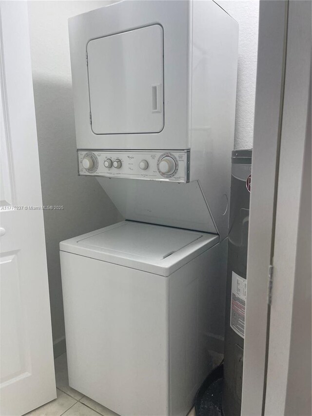 laundry area featuring light tile patterned floors, stacked washer and clothes dryer, and laundry area