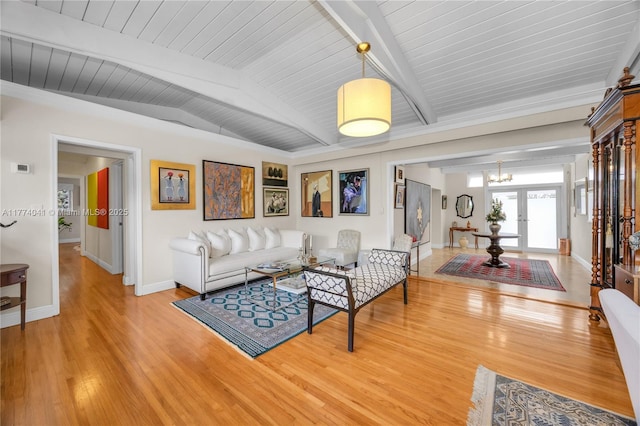 living room with lofted ceiling with beams, light wood finished floors, baseboards, an inviting chandelier, and wood ceiling