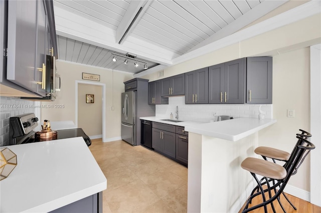 kitchen with a kitchen breakfast bar, light countertops, a sink, a peninsula, and appliances with stainless steel finishes