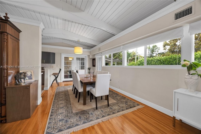 dining space with light wood-style flooring, lofted ceiling with beams, baseboards, and visible vents